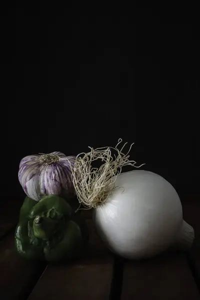 Tahta masa üzerinde soğan, yeşil biber ve sarımsak.