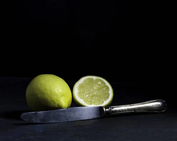 YELLOW LEMON CUT WITH AND OLD KNIFE ON DARK BACKGROUND