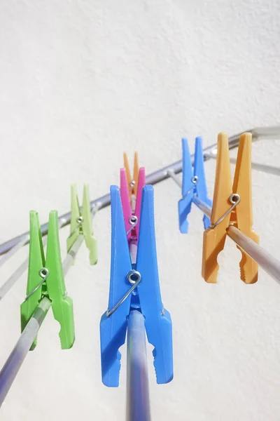 CLAMPS FOR HANGING CLOTHES ON THE WHITE WALL LIGHTED BY THE SUN . WORK AT HOME — Stock Photo, Image