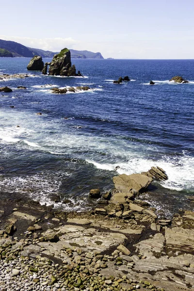 SEA LANDSCAPE WITH ROCKS ON THE SHORE AND LARGE ROCKS IN THE HORIZON IN THE NORTH OF SPAIN — Stock Photo, Image