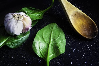 Taze ıspanak ve ızgarada kaşık ile sarımsak.