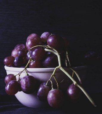 Beyaz kâse ve Karanlık Arkaplanda Üzüm Demeti