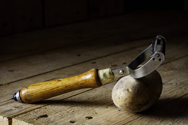 POTATOES WITH CUTTER ON WOODEN TABLE. RUSTIC FOOD PHOTOGRAPHY