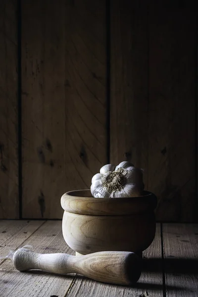 Witte knoflook met houten mortel op houten tafel en donkere achtergrond. Rustieke Food Photography — Stockfoto