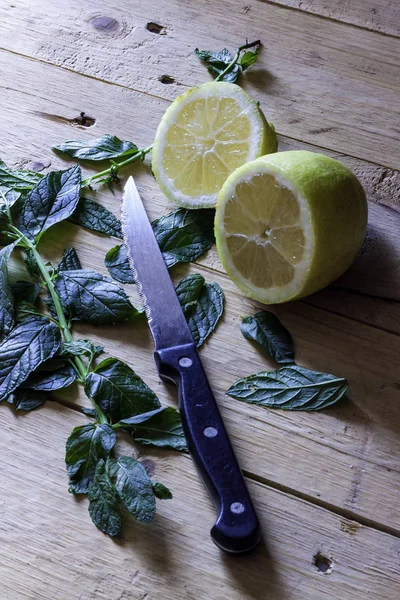 Sarı limon kesimi Mutfak Bıçağı Ahşap masa ve Aromatik Yapraklar