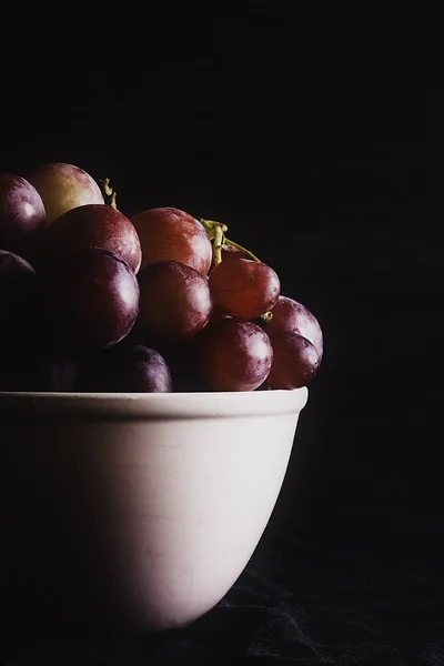 Bunch van druiven op witte schaal en donkere achtergrond — Stockfoto