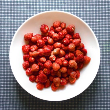 Masadaki tabakta olgun kırmızı çilekler. Üst görünüm.