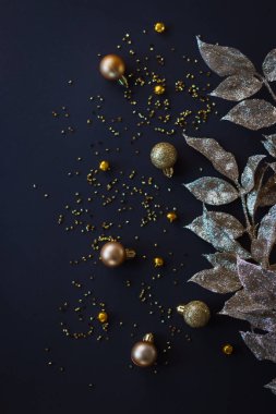 Koyu arkaplanda altın Noel süsü. Molozlar ve yapraklar. Düz yatıyordu.