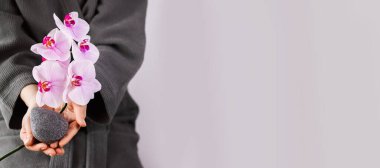 Doğal manikürlü kadın elleri güzel pembe orkideler ve konjac süngeri tutuyor..