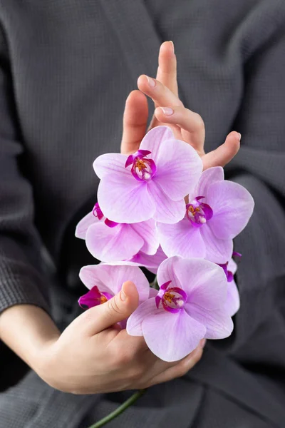 Vrouwen handen met natuurlijke manicure met mooie roze orchideeën. — Stockfoto