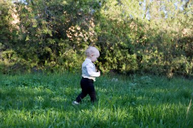 Küçük çocuk yürümek ve açık havada yeşil çimlere çalıştırın