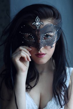 Gizemli esmer, mavi gözlü, pembe dudaklı, karnaval Venedik siyah dantelli güzel maskeli, baştan çıkarıcı kameraya bakan genç bir kadın.