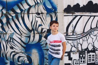 Şık çocuk okul öncesi çocuk rahat kot pantolon ve tişörtle duvarın yanında grafiti, zebra çizimi