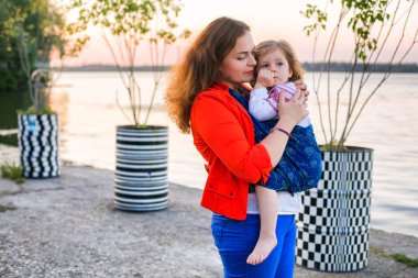 Güzel günbatımı portresi anne ve tatlı, yorgun bebek bebek. Yürüyüş sırasında şalgam takar, aktif çalışan anne.