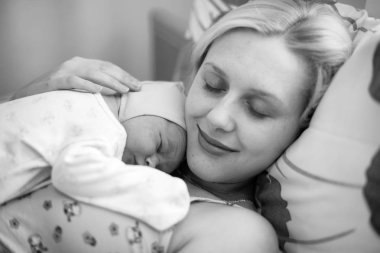 Black and white photo of happy mother and just few hours newborn baby lay with closed eyes in maternity hospital clipart