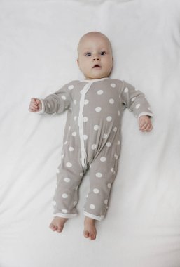 Gri bir elbise içinde aylarca yatakta yatan tatlı bir bebek. Aile, yeni hayat, çocukluk gebeliği