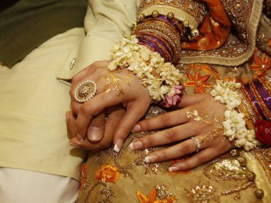 Hint Pakistanlı nişanlı gelin ve damat mücevher yüzükleri, bilezikler ve altın kına ile el ele tutuşuyorlar.