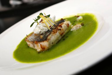 Izgara beyaz balık filetosunu sebze yeşili kremalı sos ve harika restoran dekorasyonu, şefin yaratılışı, gurme mutfağı.