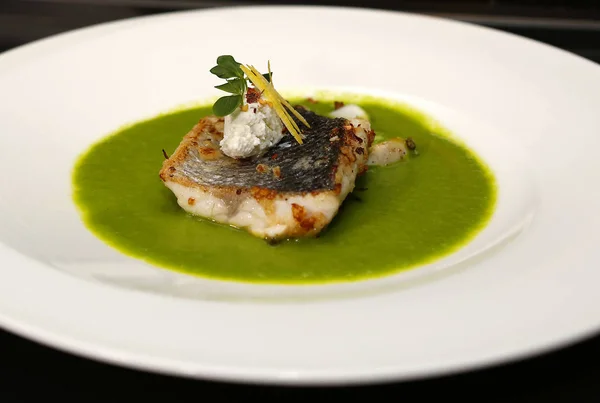 Close up of grilled white fish fillet with vegetable green creamy sauce and great restaurant decoration, high cuisine, seafood dinner