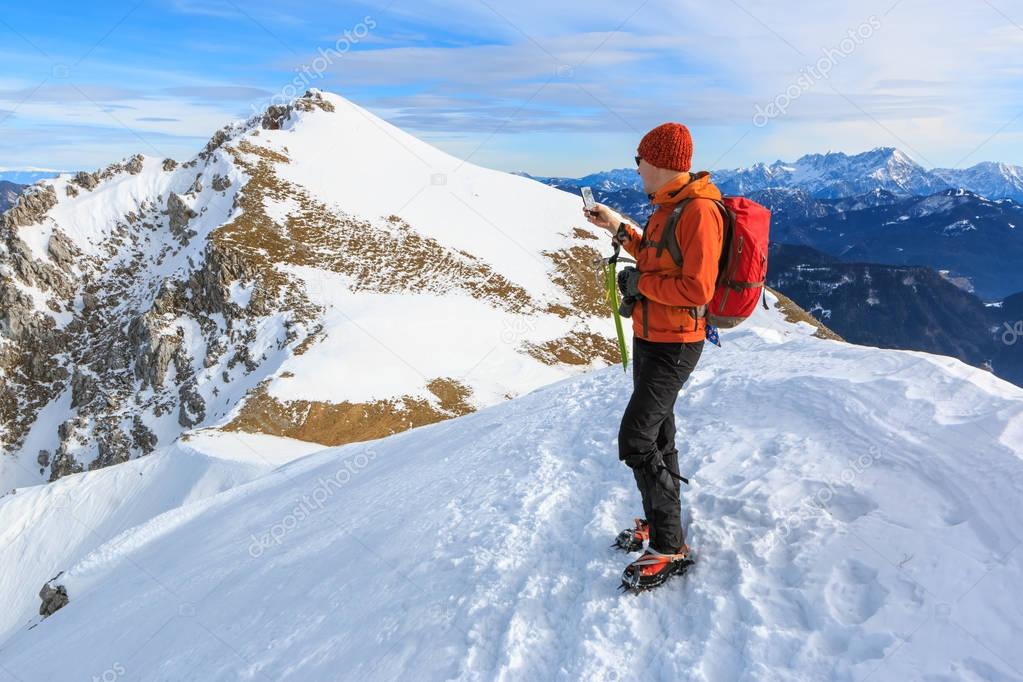 The mountaineer photographing with the mobile phone on the top of the ridge of the Begunjscica mountain, Slovenia