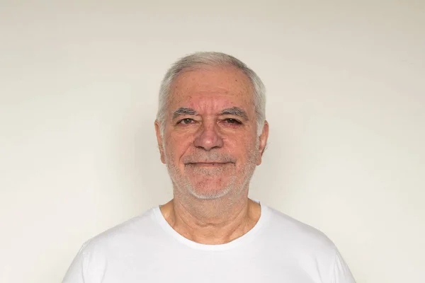 Yaşlı adam kıdemli beyaz t-shirt. Duvarın hemen yanında. Sağlıklı, mutlu.