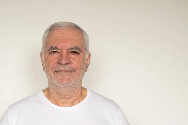 Yaşlı adam kıdemli beyaz t-shirt. Duvarın hemen yanında. Sağlıklı, mutlu.