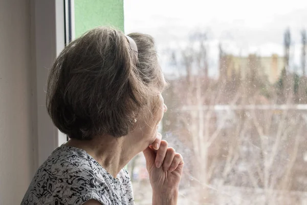 Triste anciana solitaria mirar al lado de la ventana allone deprimido — Foto de Stock