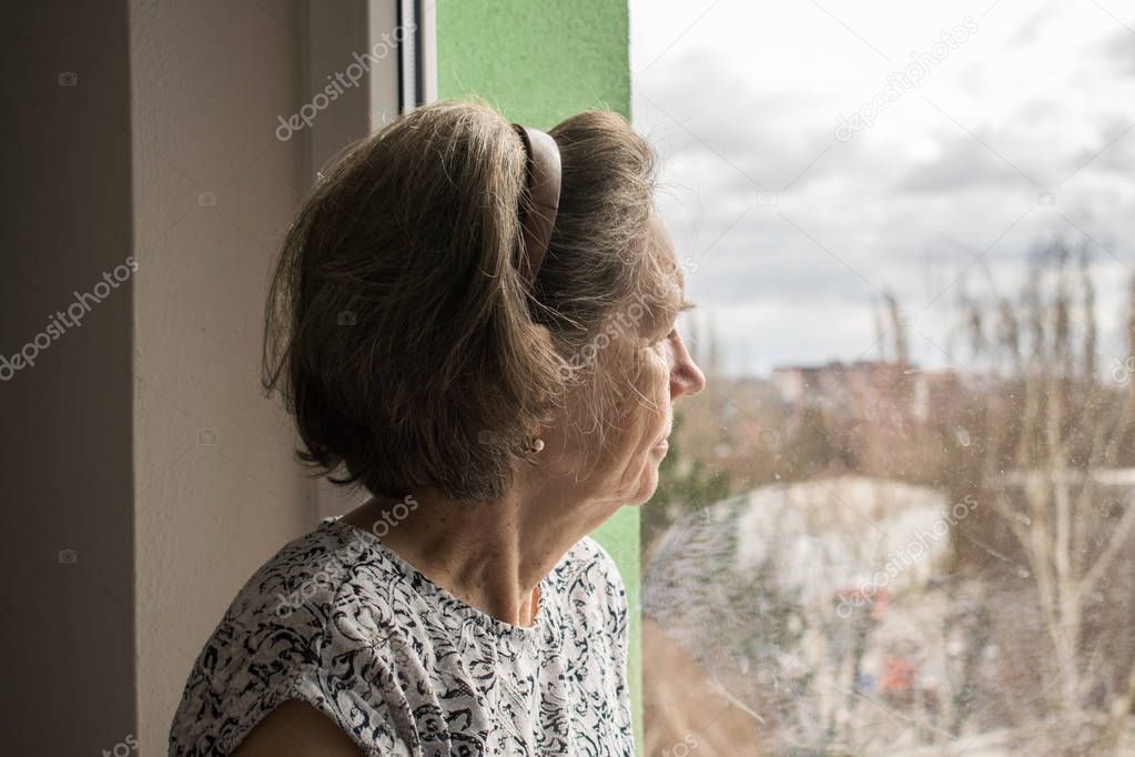  sad lonely old woman look next to  window allone depressed 