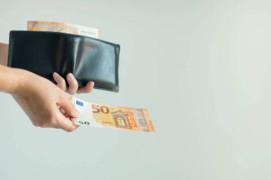 Kısa cüzdandan bir banknot seçen ve Avrupa para birimiyle ödeme yapan bir el..