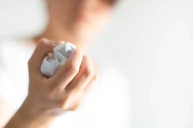 A person holding and squeezing document paper in close-up; selected focus at the hand; with copy space. The concept of pressure from rejected work and problem in business or idea failure.