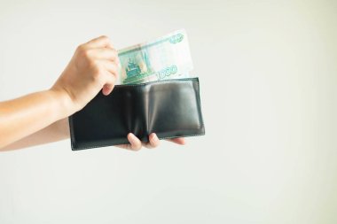 Kısa cüzdanı tutan ellerin yakın çekimi ve bir el Ruouble veya Rub para birimini ortaya çıkarır; cüzdandan beyaz arka planda bir şey ödemek için. 