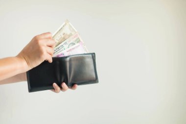 Close-up of hands holding a short wallet and one hand bring out the money in the currency of Rupee or INR; from the wallet to pay for something on white background. 