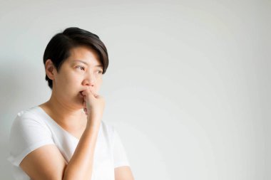 Dalgın, endişeli bir kadının yan portresi; başparmağın tırnağını ısırarak ve boş gözlerle ileriye bakarak ifade; kopyalama alanı ile beyaz arka planda.