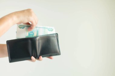 Kısa bir cüzdan tutan eller ve bir el Rouble veya RuB para birimini ortaya çıkarır; beyaz arka planda bir şey ödemek için cüzdan. Banknotlarda seçici odak.