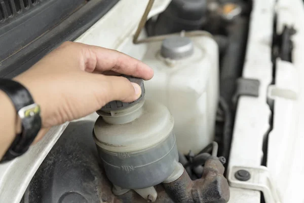 man\'s hand checking level of brake fluid tank - Car maintenance