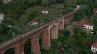 Sisli gökyüzü ile tepeler arasında klasik tuğla köprü. Eski demiryolu köprüsü.