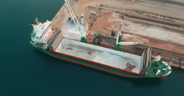Flygfoto. Skeppet anlände till hamnen. lossning av lastfartyg med grävmaskin inne i fartyget, lossning av bulklast. — Stockvideo