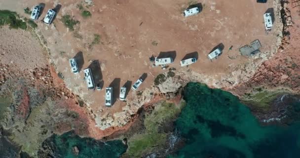 Vista aérea de muchas camionetas campistas en un estacionamiento. Filmación aérea del mar escénico. Vacaciones en el camino . — Vídeo de stock