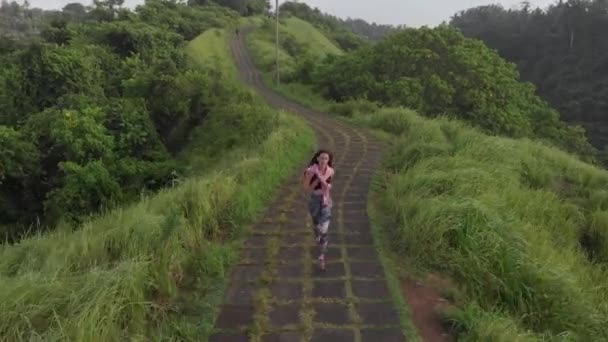 Κορίτσι Κολάν Τρέχει Κατά Μήκος Του Δρόμου Μεταξύ Της Ζούγκλας — Αρχείο Βίντεο