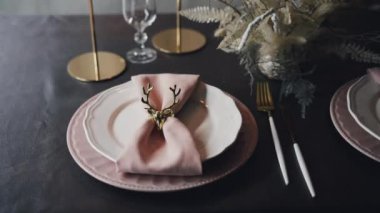 Pembe peçeteli tabaklar ve servis edilen Noel masasında geyik.