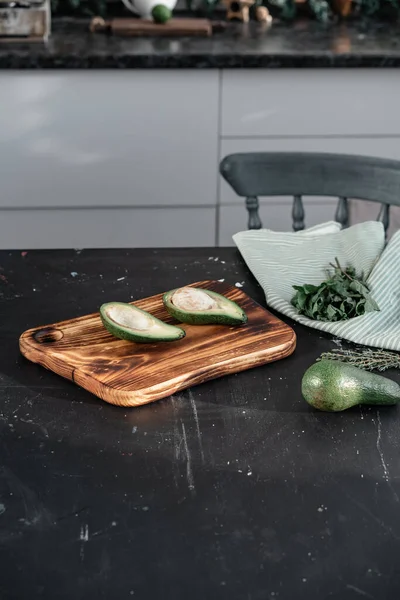 Κομμένο αβοκάντο βρίσκεται στο τραπέζι της κουζίνας — Φωτογραφία Αρχείου