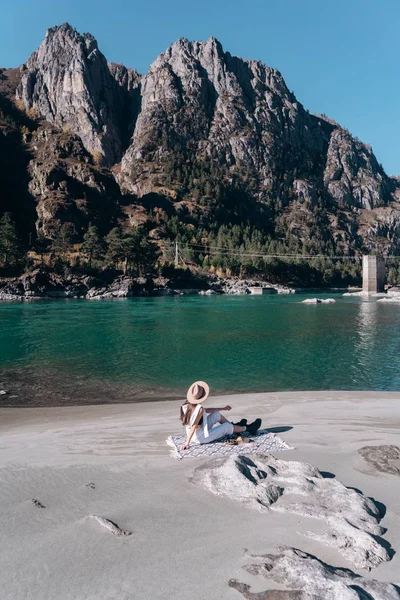Chica sentada en la orilla de un río de montaña — Foto de Stock