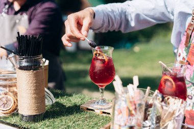 Barmen bardağı kırmızı kokteyl ile süslüyor.