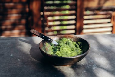 Seramik tabakta, beton bir masada bıçakla guacamole.
