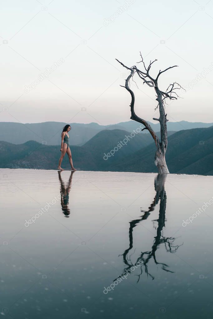 Girl on top of a white mountain with blue lakes and springs in Mexico hierve del agua