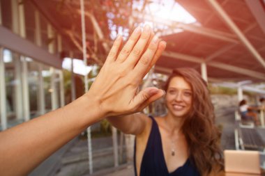 Dost canlısı genç kadın ve erkek gülüyor ve beşlik çakıyor.