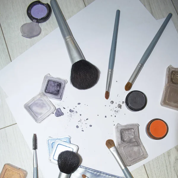 Makyaj aksesuarlarının fotoğrafı masanın her tarafına saçılmış.