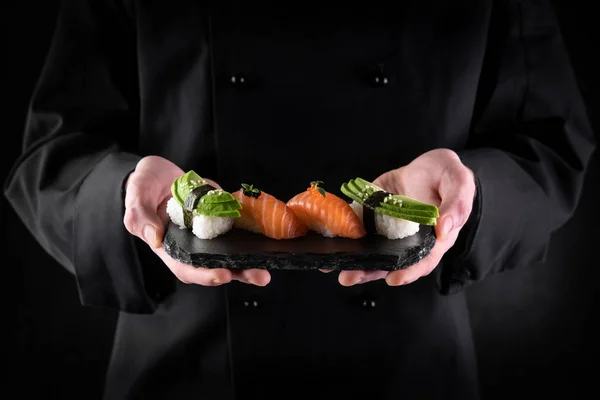 Sushi Serveras Stenskiffer Kockens Händer Mörk Bakgrund Dekorerad Sashimi Nigiri — Stockfoto