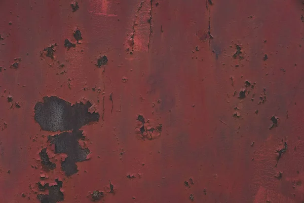 Rusty red metal grunge texture background. Old worn iron plate with peeled off dark red paint and scratches. Toned, close up, copy space