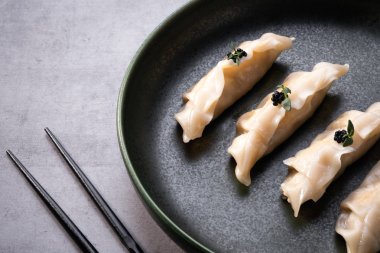 Gri taş masa zemininde Japon gyoza köftesi. Geleneksel Asya yemekleri. Somon, soya sosu ve çubukla Çin mantısı pişirilmiş. Boşluğu kopyala, kapat
